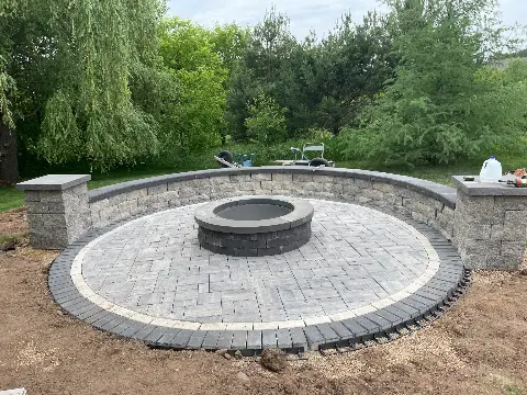 Circular stone fire pit with paver patio in backyard setting